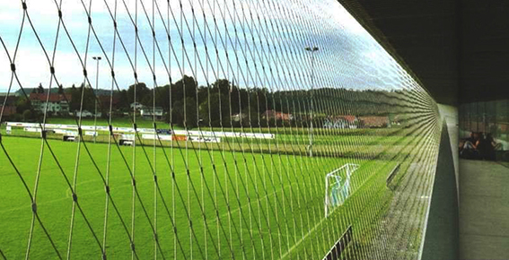 Fußballplatz mit Sicherheitsnetz im Vordergrund zur Zuschauertrennung
