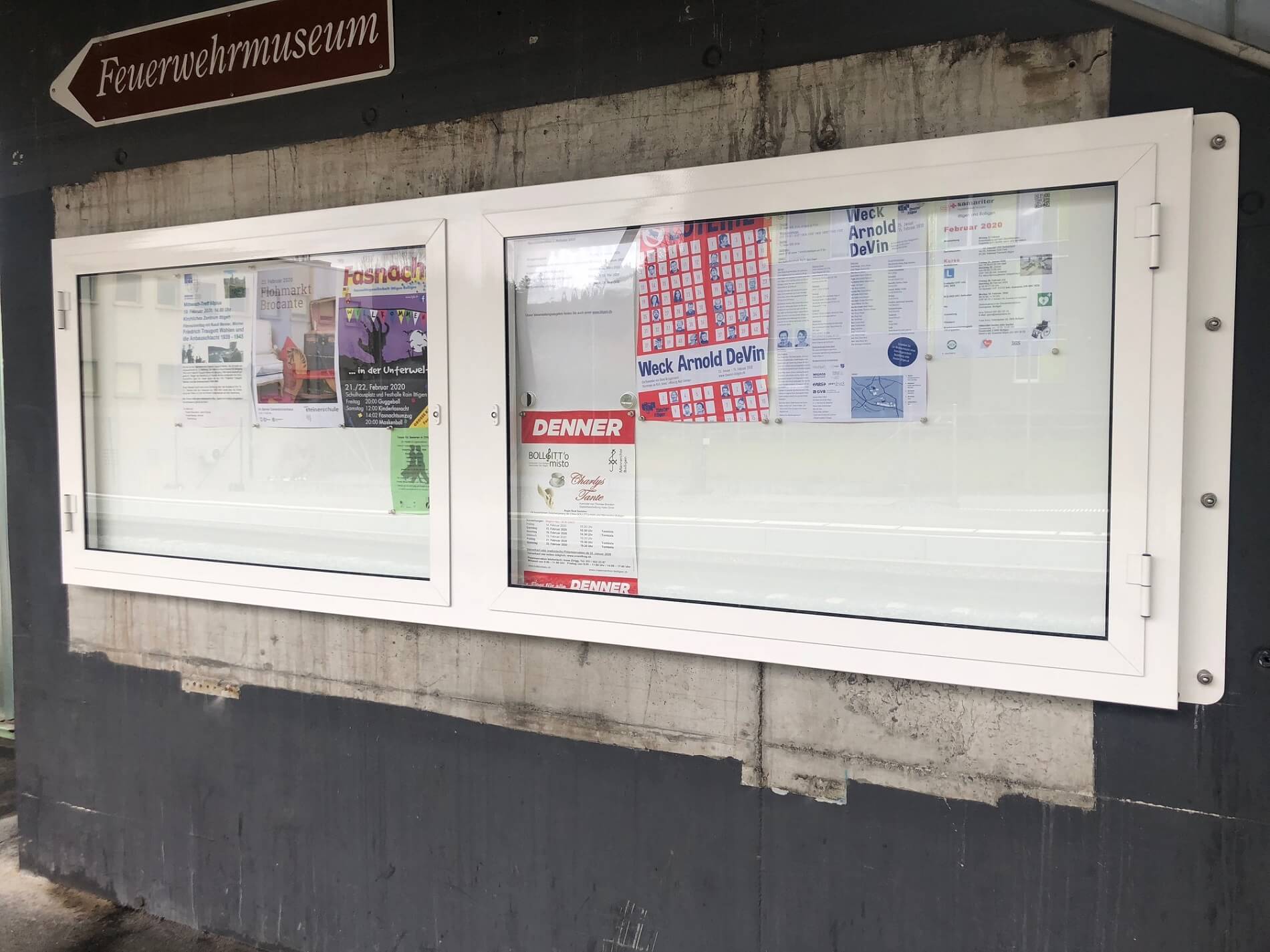 Un panneau d'annonce avec plusieurs affiches colorées et un panneau indicateur du musée des pompiers