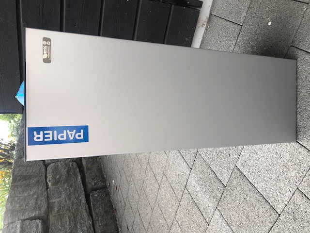 Silberner Papiermüllbehälter auf einer Terrasse im Freien mit blauem Etikett 'Papier'