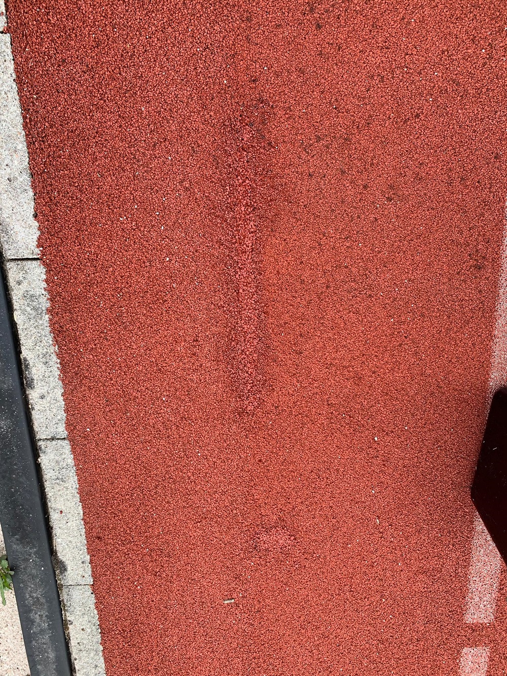 Surface de piste rouge avec goudron et bordure de trottoir