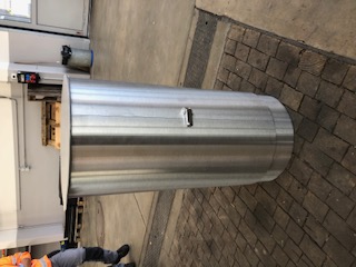 Une armoire cylindrique en acier inoxydable dans un environnement d'atelier, idéale pour le rangement en milieu industriel.