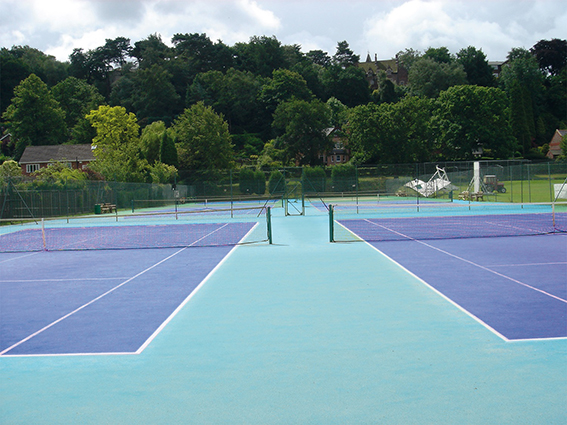 Blauer Tennisplatz mit drei Spielfeldern in grüner Umgebung