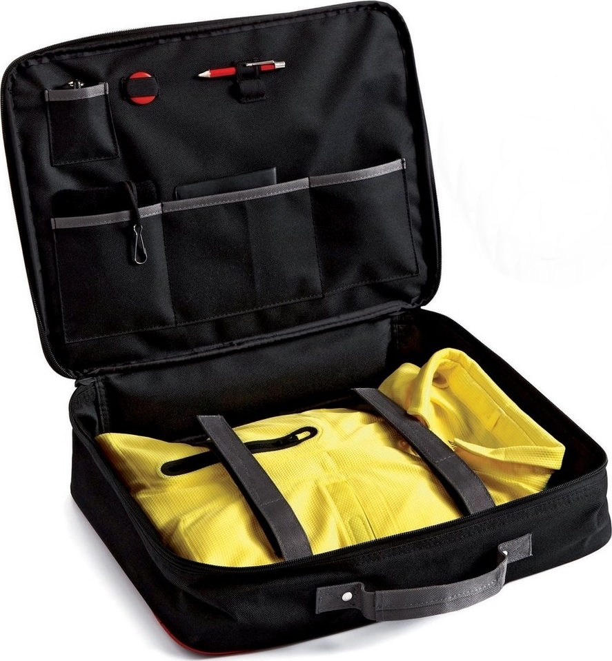 Sac de voyage noir ouvert avec plusieurs compartiments, rempli d'une chemise jaune