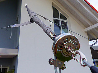 Gros plan sur un système de fixation de voile solaire sur une maison moderne avec des poulies et des câbles.