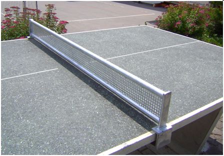 Graue Outdoor Tischtennisplatte mit einem stabilen Metallnetz auf einem Platz vor bunten Blumenbeeten
