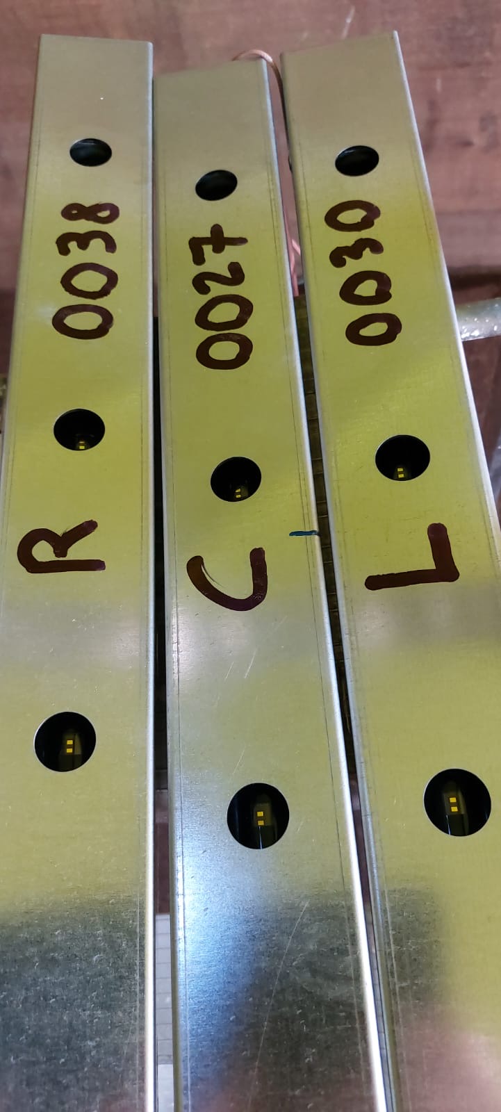 Drei Stahlträger mit den Aufschriften R0038, J0027 und L0020 in einer Lagerhalle