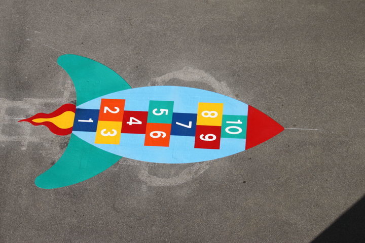 Bunte Rakete als Hüpfspiel auf Asphalt, mit nummerierten Feldern von 1 bis 10.