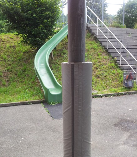 Grüne Rutsche neben einer Treppe und ein gepolsterter Pfosten auf einem Spielplatz