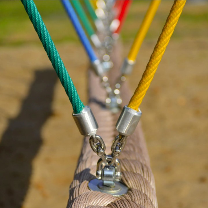 Detailansicht von farbigen Stahlseilen mit robusten Edelstahl-Verbindern an einem Spielplatzgerät im Außenbereich