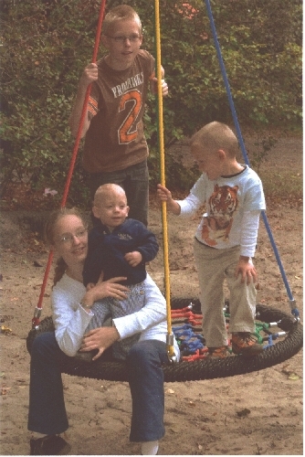 Vier Kinder sitzen fröhlich auf einer Reifenschaukel und genießen den Tag im Park.