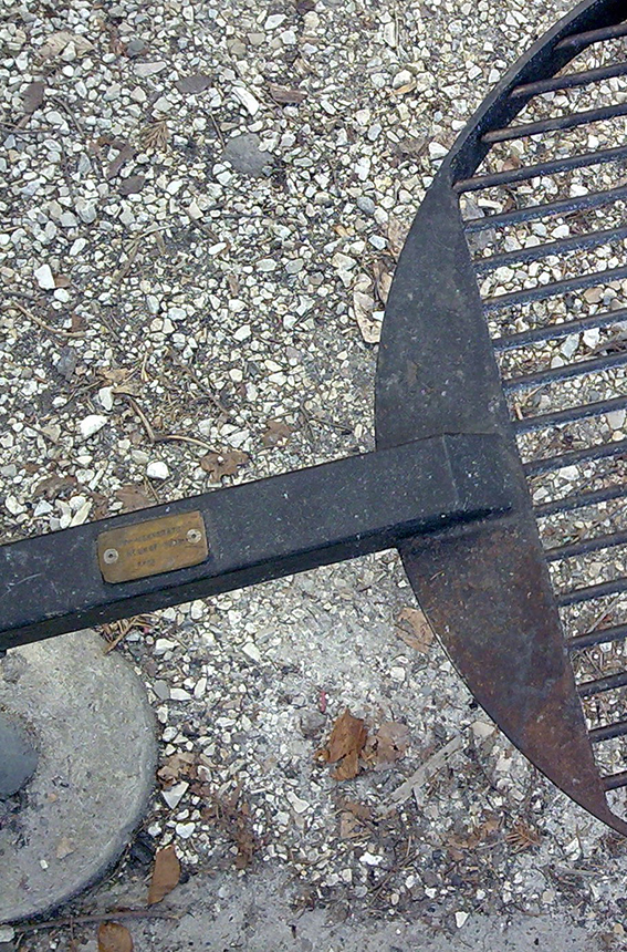 Runder Grillrost auf einem kiesbedeckten Boden, geeignet für Outdoor-Kochen