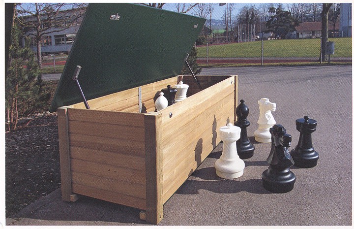 Coffre en bois ouvert avec des pièces d'échecs sur une place goudronnée
