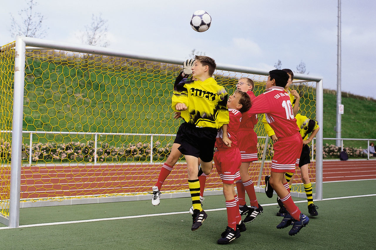 Jugendliche Fußballspieler in Aktion vor einem Tor, während der Torhüter den Ball abwehrt