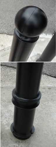 Zwei robuste schwarze Absperrpfosten auf einer Betonfläche