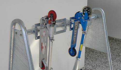 Zwei faltbare Roller, einer rot und einer blau, sind an einem Ständer befestigt.