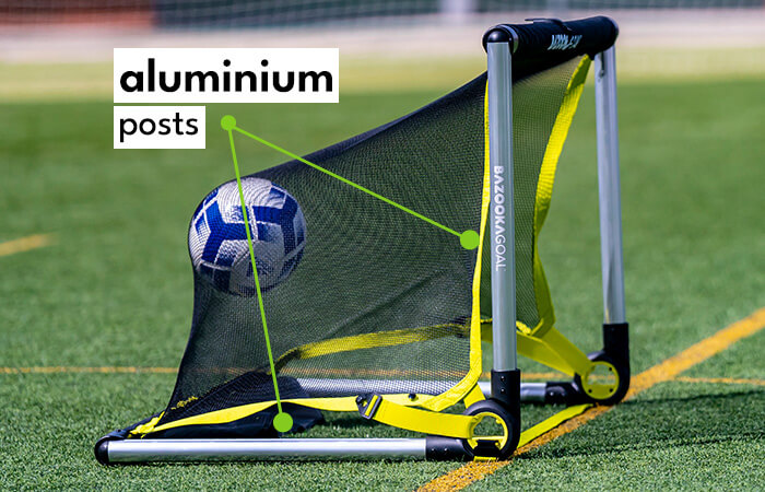 Ein tragbares Fußballtor mit Aluminiumrahmen und einem Ball, das auf einem Sportplatz steht.