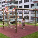 Plusieurs enfants grimpent et jouent sur un échafaudage à grimper dans un quartier résidentiel. L'échafaudage est en bois et offre différentes possibilités de grimper.