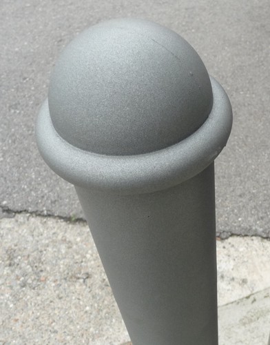 Nahaufnahme eines grauen Pollers aus Metall auf einer Straße