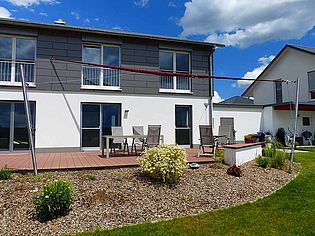 Maison moderne de deux étages avec grande terrasse et jardin soigné par temps ensoleillé