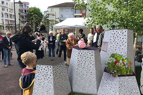 Menschen versammeln sich bei einem Bürgerfest um moderne, urbane Stadtmöbel in einer Wohngegend.