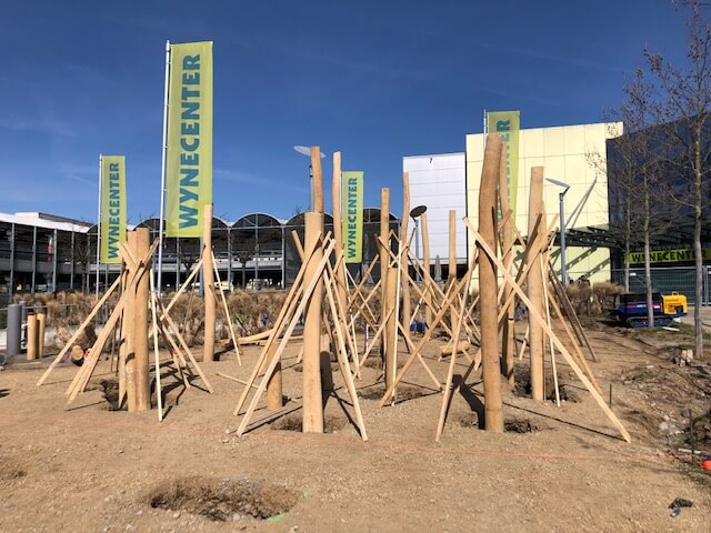 Terrain de construction avec constructions de soutien en bois et signalétique Wynencenter en arrière-plan