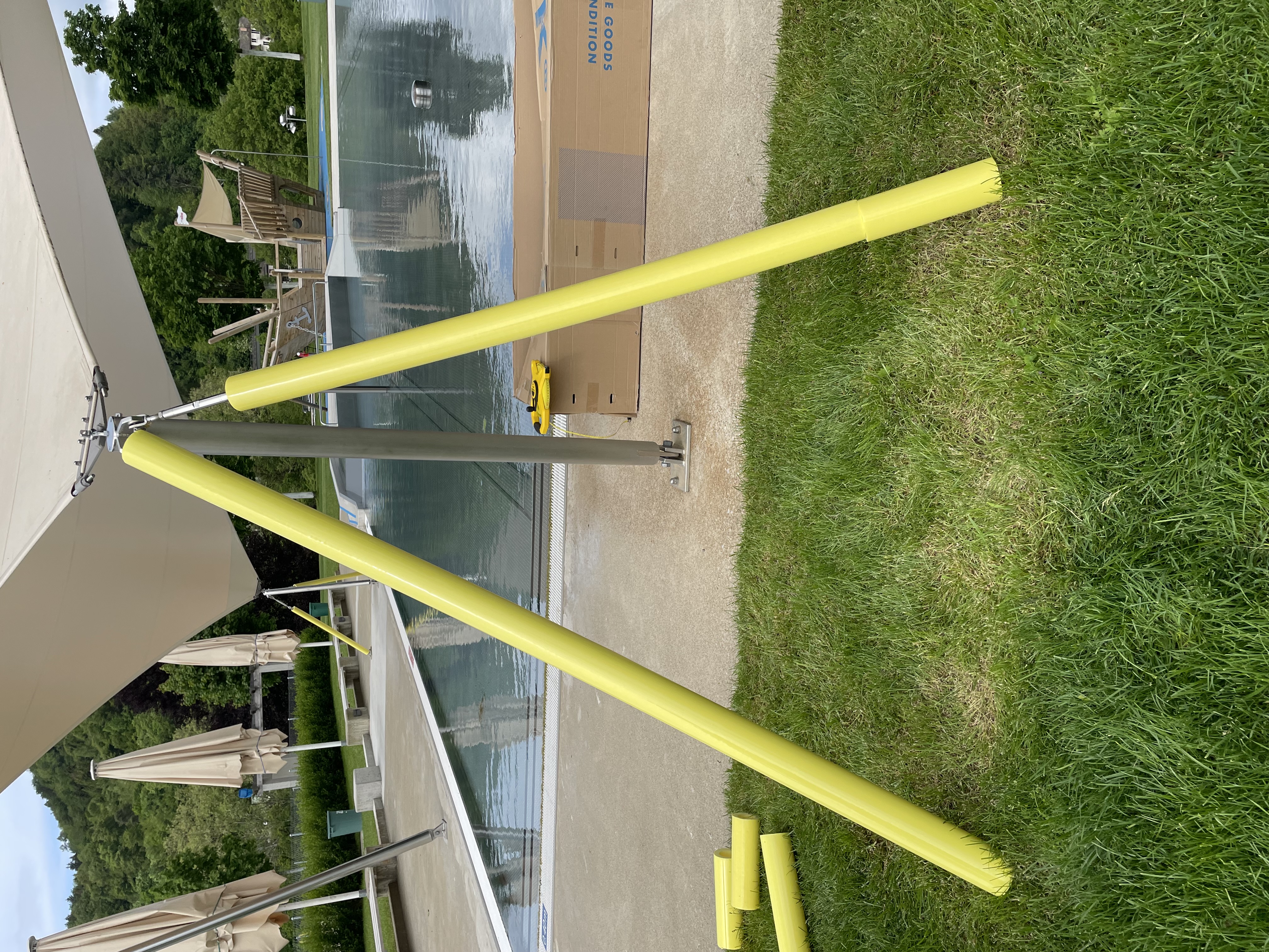 Gelbe Stangen und Sonnensegelhalterung mit Pool im Hintergrund