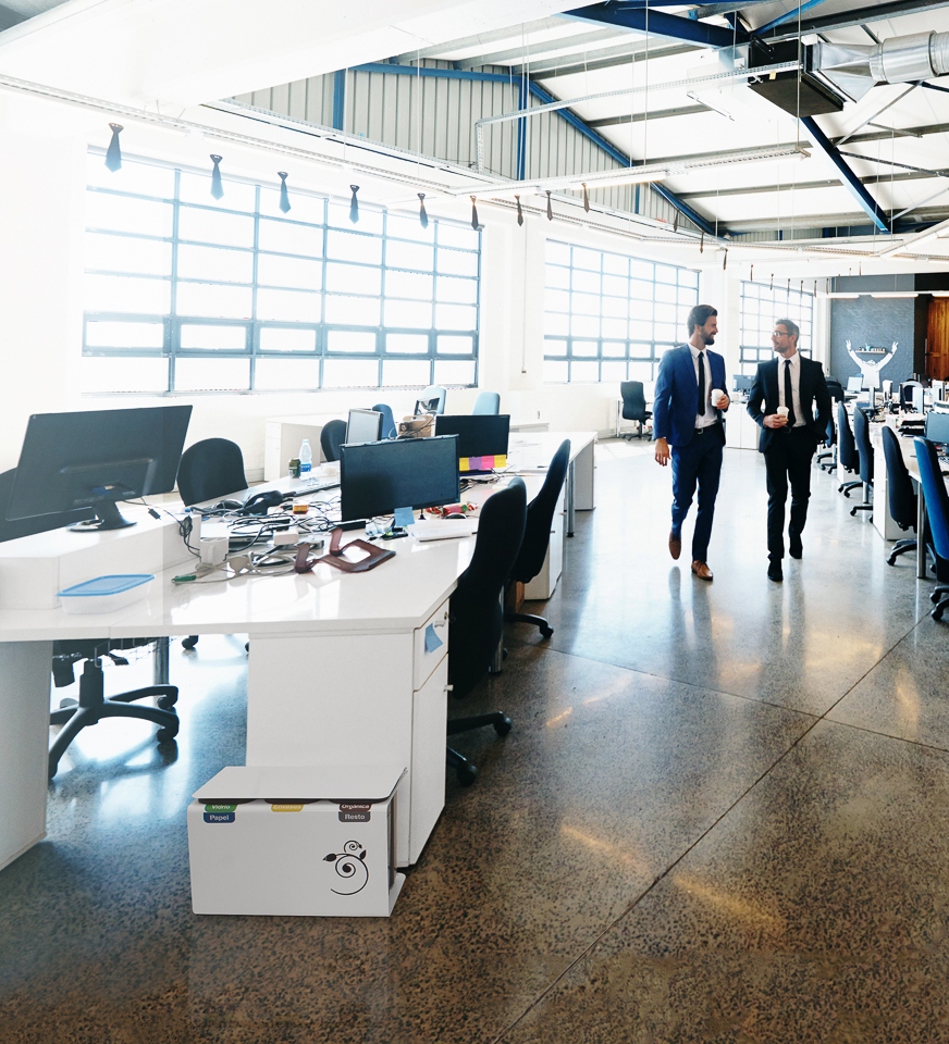 Deux hommes en costume traversent un bureau moderne, inondé de soleil et doté d'espaces de travail ouverts.