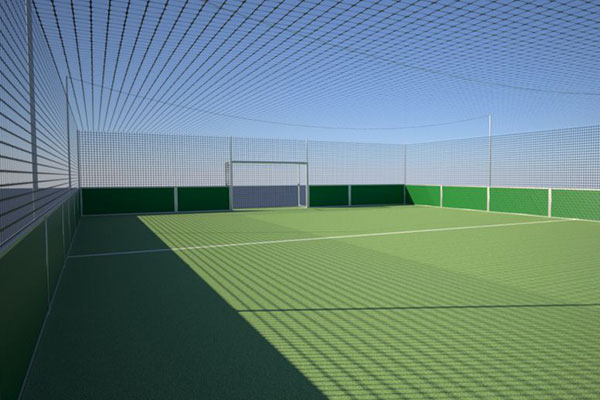 Innenansicht eines modernen Soccer-Courts mit grünem Kunstrasen und umlaufendem Ballfangnetz unter blauem Himmel